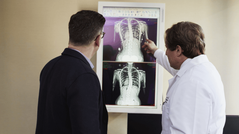 Ortopedisk lege gjennomgår et røntgenbilde med en pasient under en konsultasjon