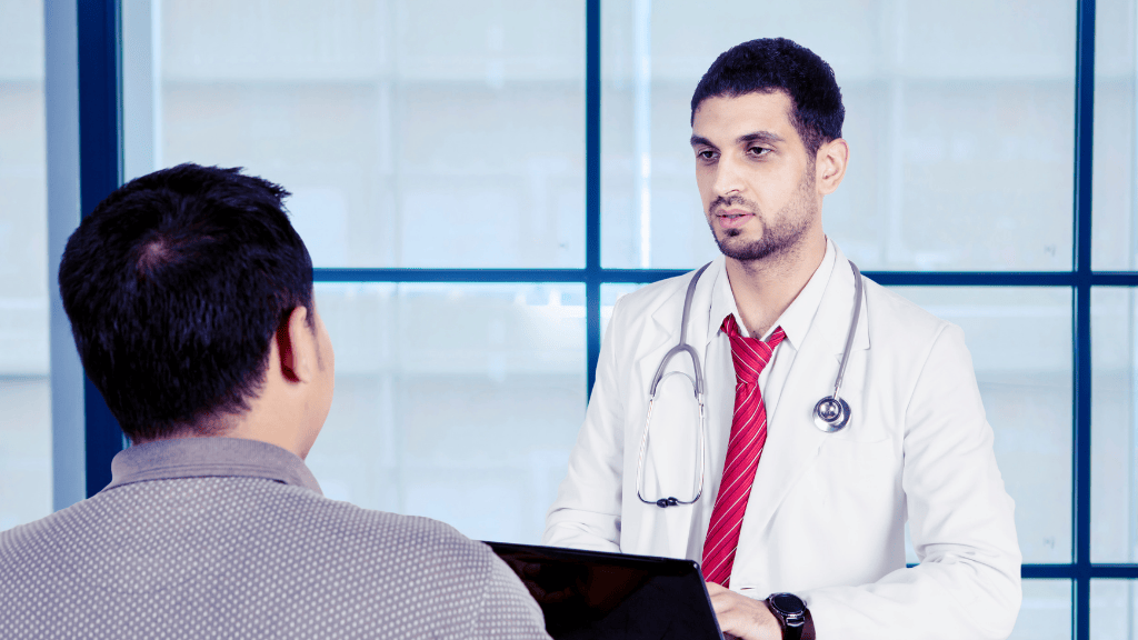 Médico hablando del procedimiento de vasectomía con un paciente varón durante la consulta