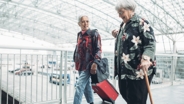 Dos mujeres mayores viajando con equipaje, una de ellas usando un bastón.